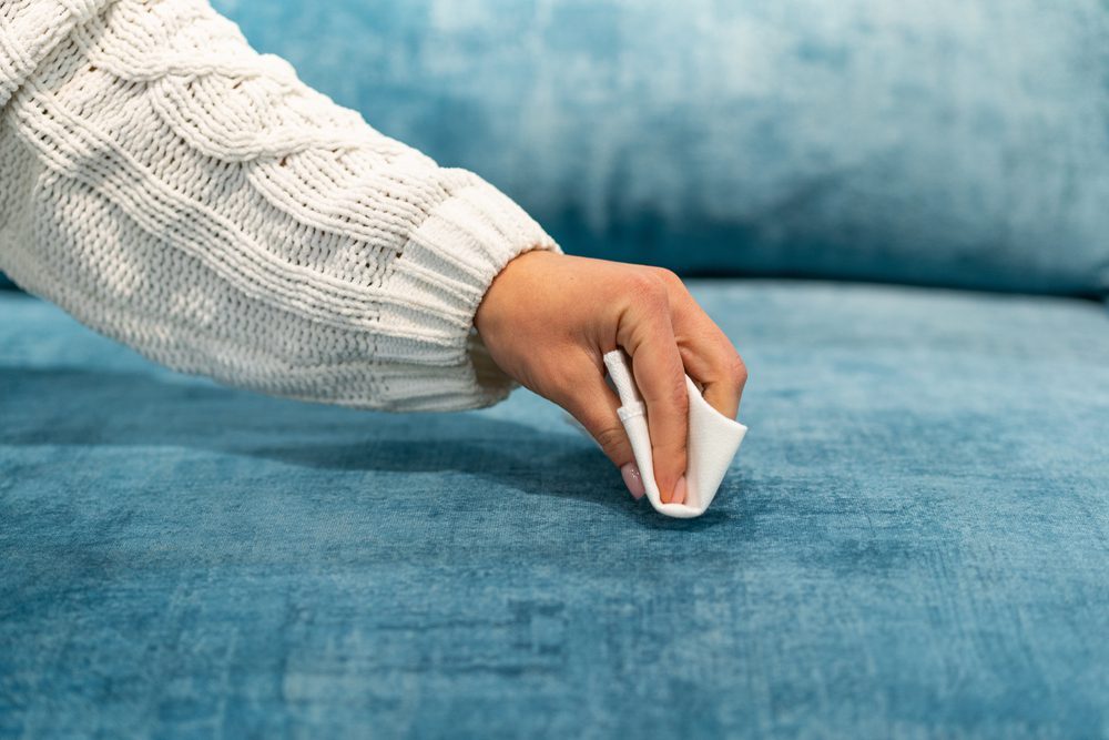 Woman,Cleaning,A,Blue,Sofa,With,White,Cloth.,Sofa,Cleaning. shutterstock 1967658367